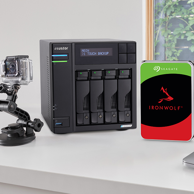 Four-bay Asustor NAS enclosure on a desk beside a Seagate IronWolf hard drive