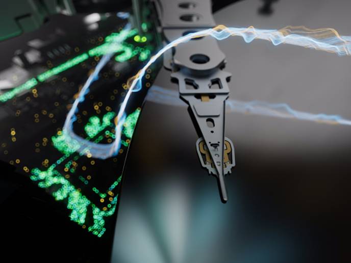 Macro view of a hard drive read/write head over a platter with green data visualization overlaid