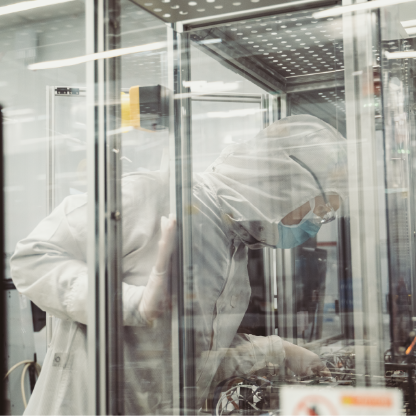 Two cleanroom workers in white protective suits behind glass partitions in a Seagate factory
