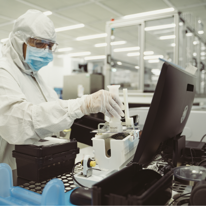 Cleanroom technician in a white suit working with lab equipment at a bench