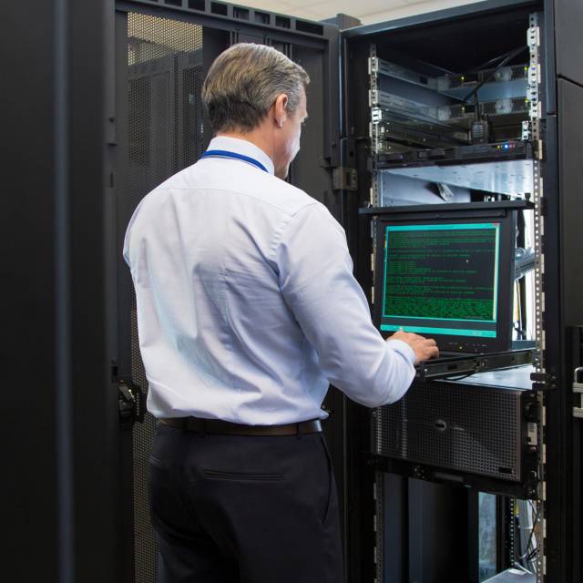 IT professional working at a laptop within a server rack in a data center running Nytro 5060 SSDs
