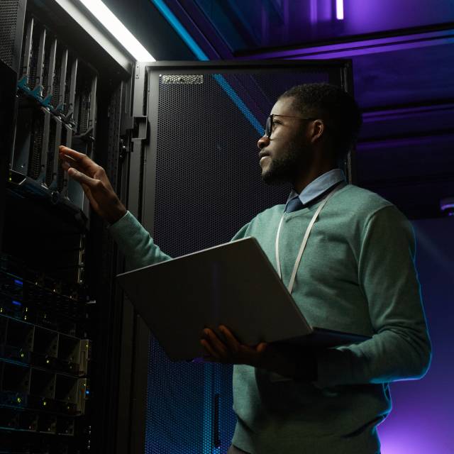 IT professional holding a laptop inspects server racks in a data center during Nytro 5060 maintenance