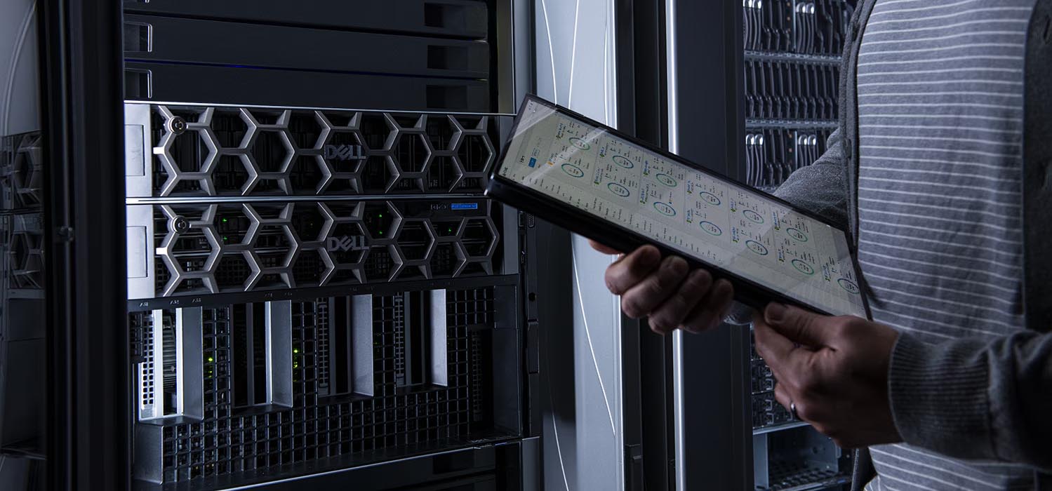 A technician sliding a component into a Dell rack server mounted in a data center cabinet