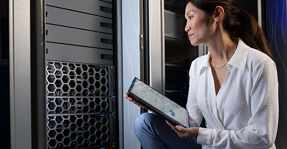 A technician holding a server component beside a rack in a data center