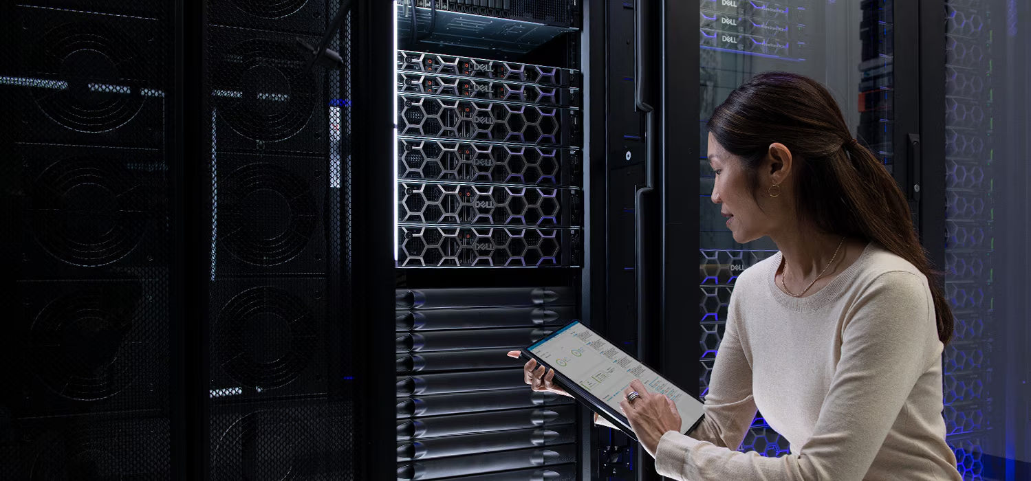 A technician working at an open server rack in a darkened data center aisle