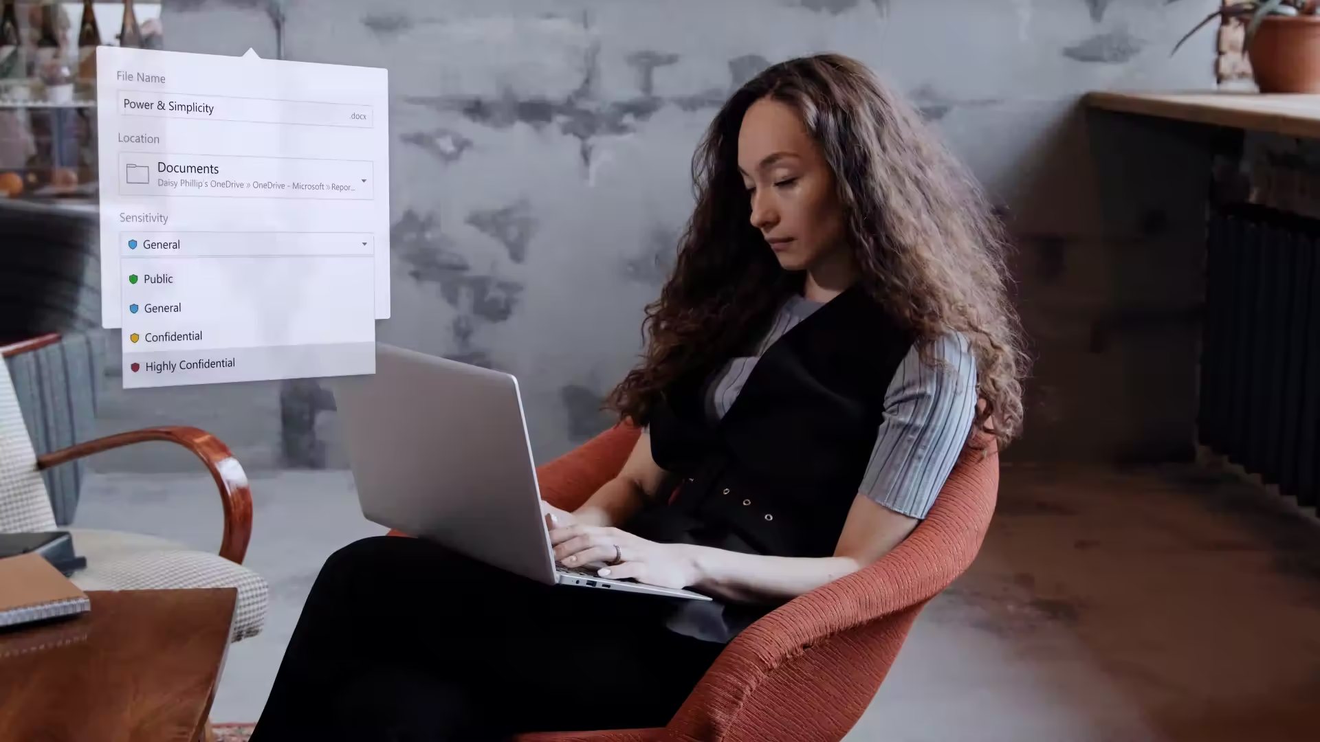 A woman working at a laptop, with a file sharing and permissions panel shown beside her.