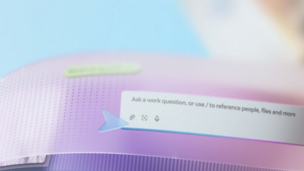 Close-up of a chat box reading &ldquo;Ask a work question, or use / to reference people, files and more&rdquo; on a pink and purple gradient.
