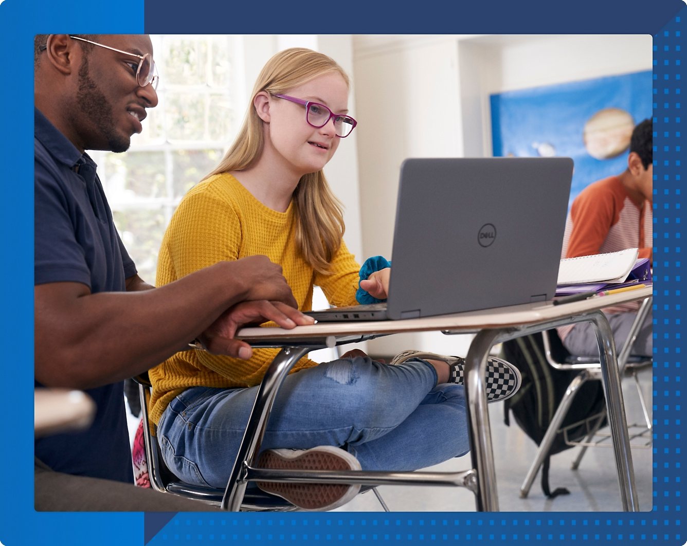 A person and another person sitting at a desk looking at a computer